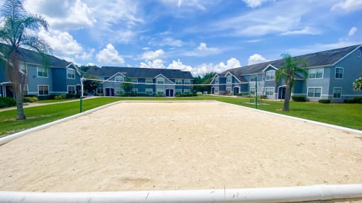 Sand volleyball court with trees and building exteriors  in the background