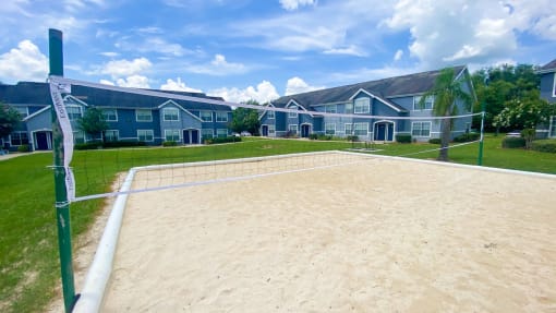Sand volleyball court with trees and building exteriors  in the background