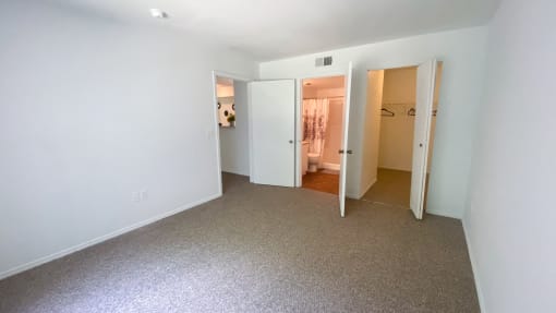 Carpeted Bedroom with view of ensuite bathroom and closet