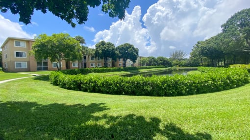 Large Grassy Courtyard with Bushes and Building Exterior with Trees