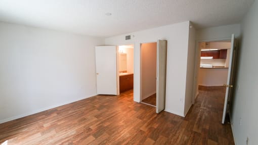 Bedroom with Hardwood Style Flooring and Open Empty Closet Next to En Suite Bathroom