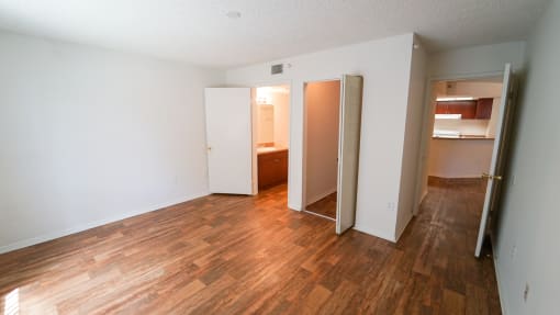 Bedroom with Hardwood Style Flooring and Open Empty Closet Next to En Suite Bathroom