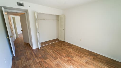Bedroom with Hardwood Style Flooring and Open Empty Closet with Sliding Closet Doors