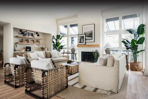 a living room with white couches and rattan chairs