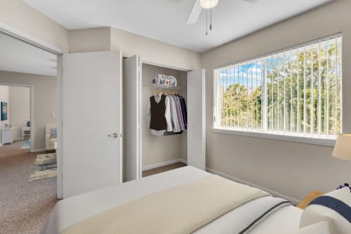 Virtually staged bedroom with large reach-in closet, multi speed ceiling fan, carpet flooring, and window for natural lighting