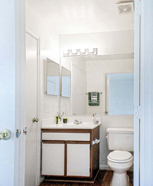 A white bathroom with a toilet, sink, and mirror.