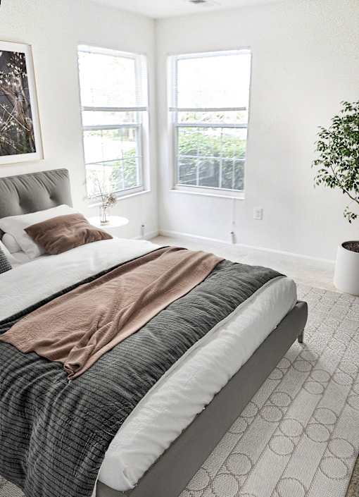 A bed with a grey headboard and a brown blanket is in the center of the room.