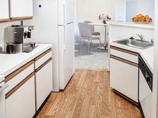 A kitchen with white appliances and wooden floors.