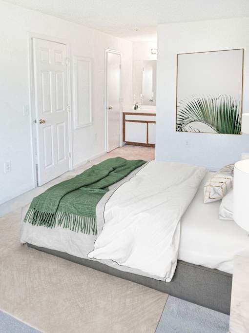 A bedroom with a bed covered in a green blanket.