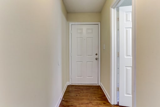 an empty hallway with a white door and a wooden floor