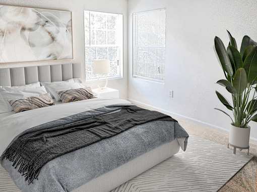 A bedroom with a large bed and a potted plant.