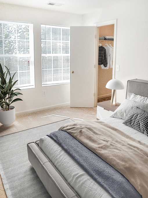 A bedroom with a bed, a potted plant, and a wardrobe.