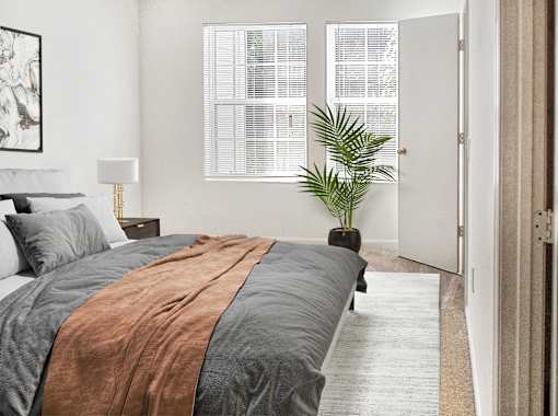 A bedroom with a large bed and a plant.