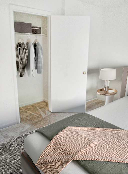 A white closet with clothes hanging inside and a bed with a pink blanket and green pillow outside.