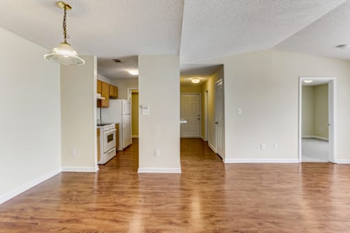 an empty living room and kitchen with a hard wood floor