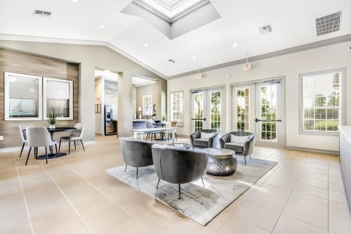 Clubhouse with several conversational seating areas along a wall of windows and glass doors.