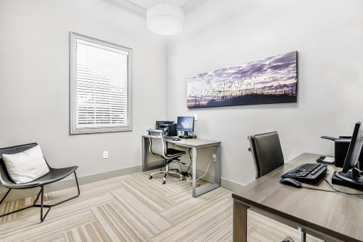 Business center with two desks, two desktop computers with printers, a guest chair, and a window.
