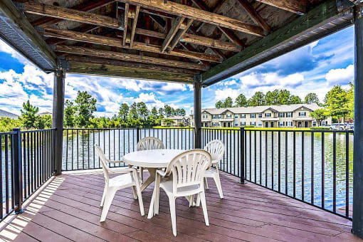 A pergola with a table and four chairs overlooking the lake.