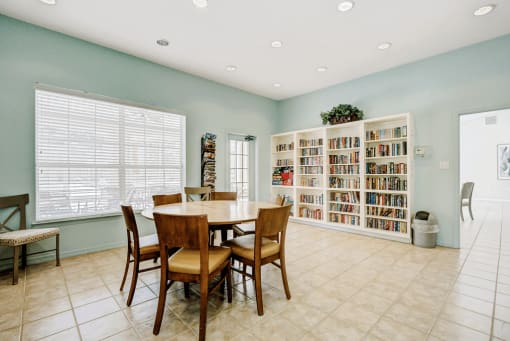 Clubhouse library featuring book shelves and table with chairs and tile flooring
