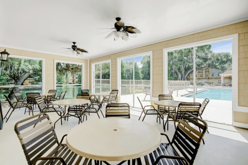 Covered lanai featuring outdoor tables and chairs, ceiling fans with lights and overlooking the pool deck