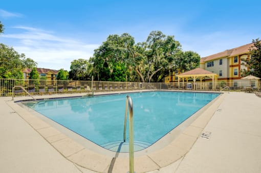 Swimming pool and pool deck featuring lounge chairs overlooking covered grill area