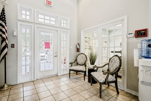 Interior view of clubhouse entrance with decorative fabric chairs, American flag, and water dispenser