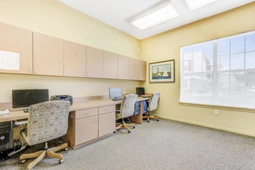 a room with two desks and three chairs and a large window