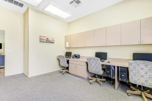 a study room with two computers and three chairs