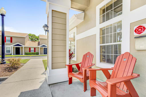 a pair of red adirondack chairs sit on a concrete patio in front of a