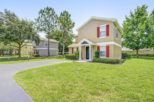 a home with a large lawn and trees in the background