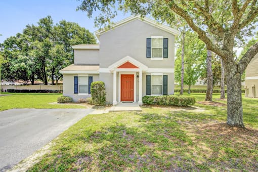 a house with a red door and a tree in front of it