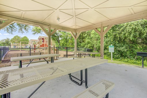 a picnic area with benches and a playground in the background