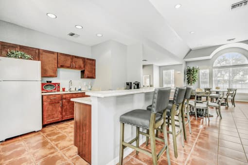 clubhouse kitchen with breakfast bar, bar stools, and wood cabinets.