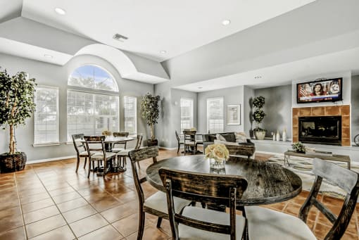 Clubhouse interior with a round table, four chairs, a fireplace, a TV, and large windows.