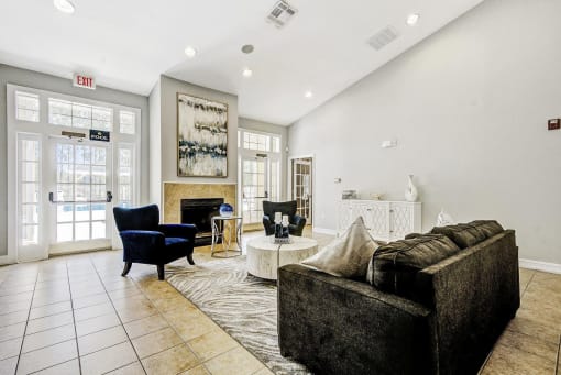 Clubhouse Seating Area with Area Rug, Couch, Coffee Table and Armchairs in Front of Fireplace Under Mounted Art