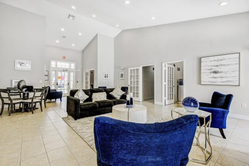Clubhouse Seating Area with Area Rug, Couch, Coffee Table and Armchairs with  Leasing Office Entry with French Doors, Armchairs and Dining Table with Chairs in the Background
