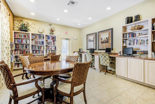 Business Center with Dining Tables with Chairs, Built in Desk with Computers, monitors and Office Chairs Next to Fully Stocked Bookshelves