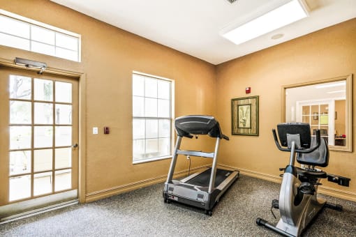 Carpeted Fitness Center with Exercise Equipment and Mounted TV