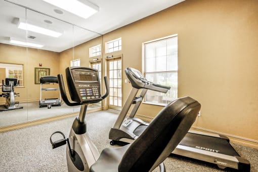 Carpeted Fitness Center with Exercise Equipment and Mounted TV