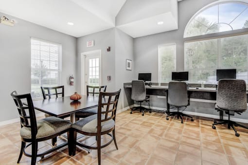 Clubhouse with a seating area and a long desk with 3 desktop computers and chairs.