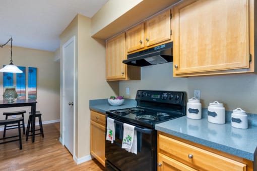 Decorated Kitchen with Black Stove Blue Counters and Blonde Wood Cabinets