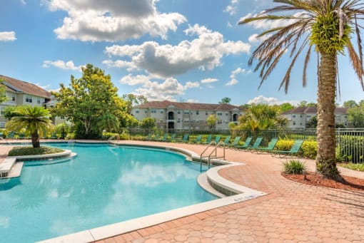 Swimming Pool and Sun Deck with Lounge Chairs with Trees and Building Exteriors in the Background