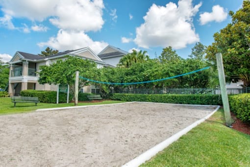 Sand Volleyball Court Surrounded by Trees and Shrubs with Building Exterior in The Background