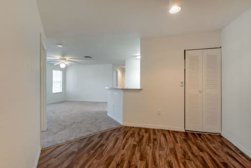 Dining Room with Hardwood Style Flooring with Sliding Closet with Carpeted Living Room Next to Breakfast Bar