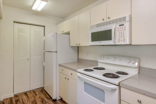Kitchen with White Cabinets and Appliances with Grey Counters and Sliding Closet Door