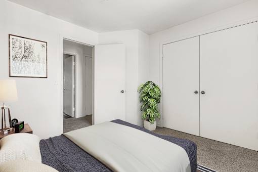 Bedroom with white closet doors and plant at Tierra Antigua Apartments, ARIZONA