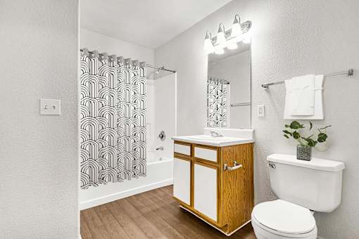 Bathroom with wood vanity and patterned shower curtain at Tierra Antigua Apartments, Mesa, 85207
