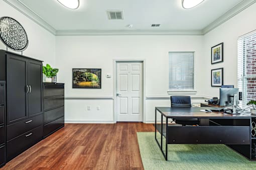 A black desk with a computer and chair in a room with a white door.
