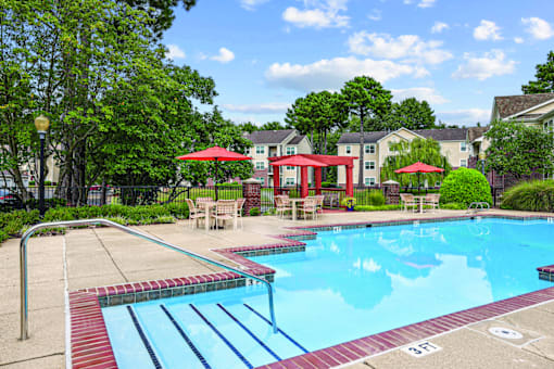 A pool with a slide and a red umbrella.