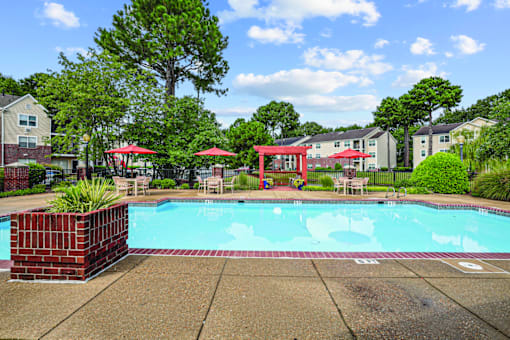 A pool surrounded by a red fence and trees.